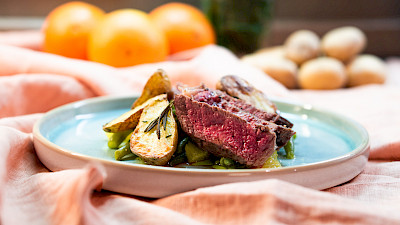 Entrecôte mit Ofenkartoffeln auf grünen Bohnen und Orangen